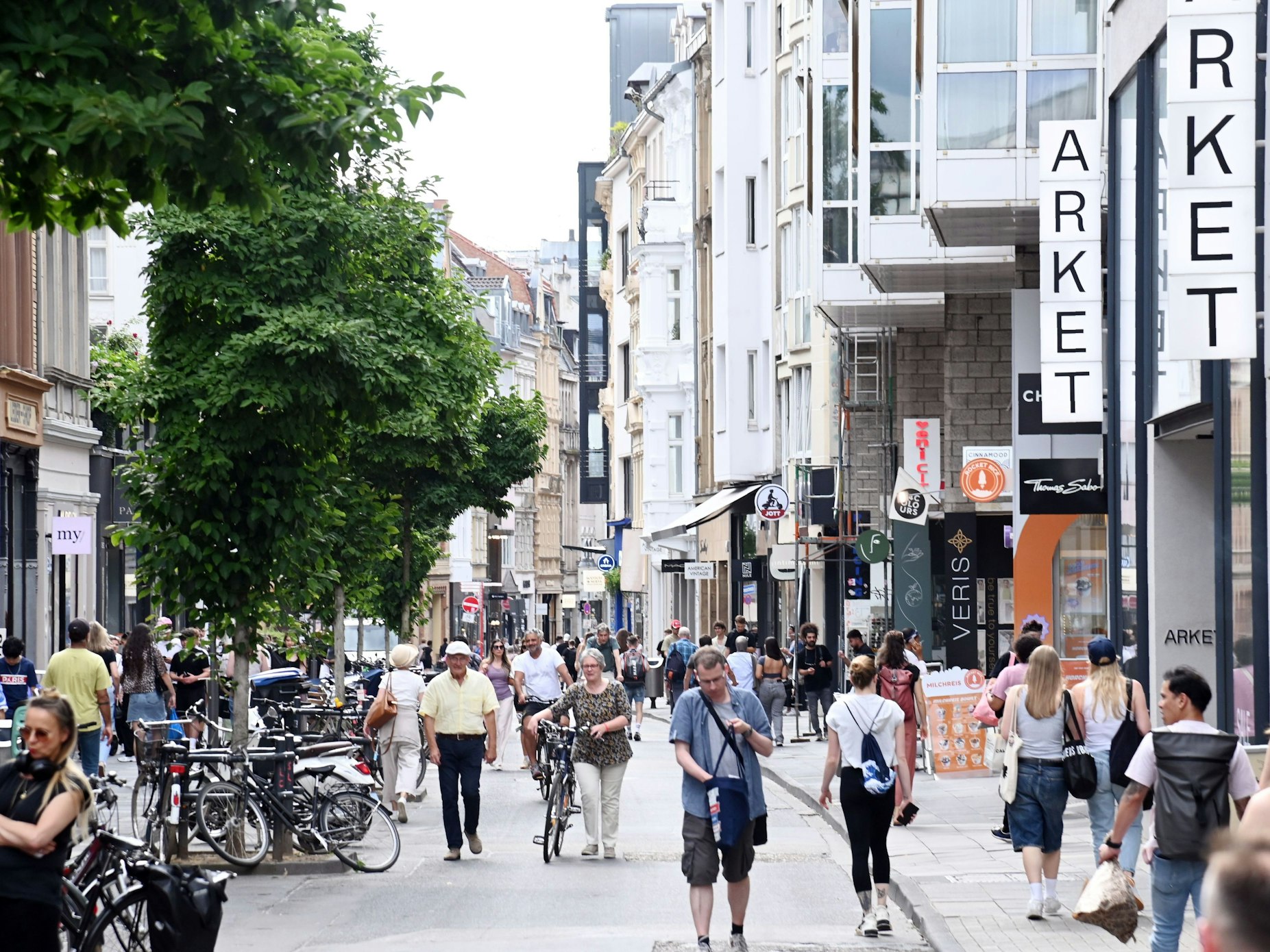 Menschen gehen über die Ehrenstraße in Köln. Es ist eine der beliebtesten Shoppingmeilen der Stadt.