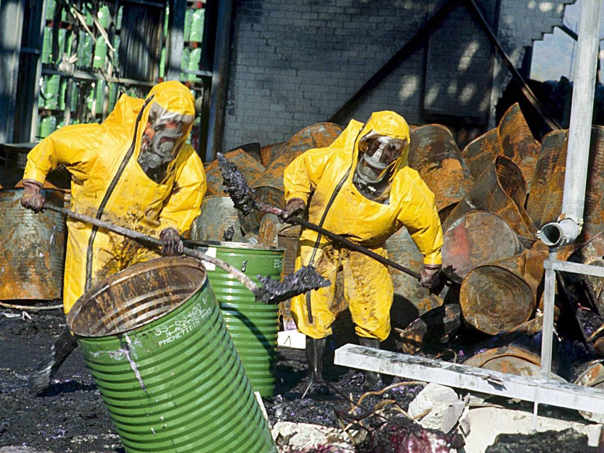 Feuerwehrleute in Schutzkleidung räumen einige Tage nach einem Brand in einem Chemiewerk des Schweizer Chemieunternehmens Sandoz die Trümmer auf.