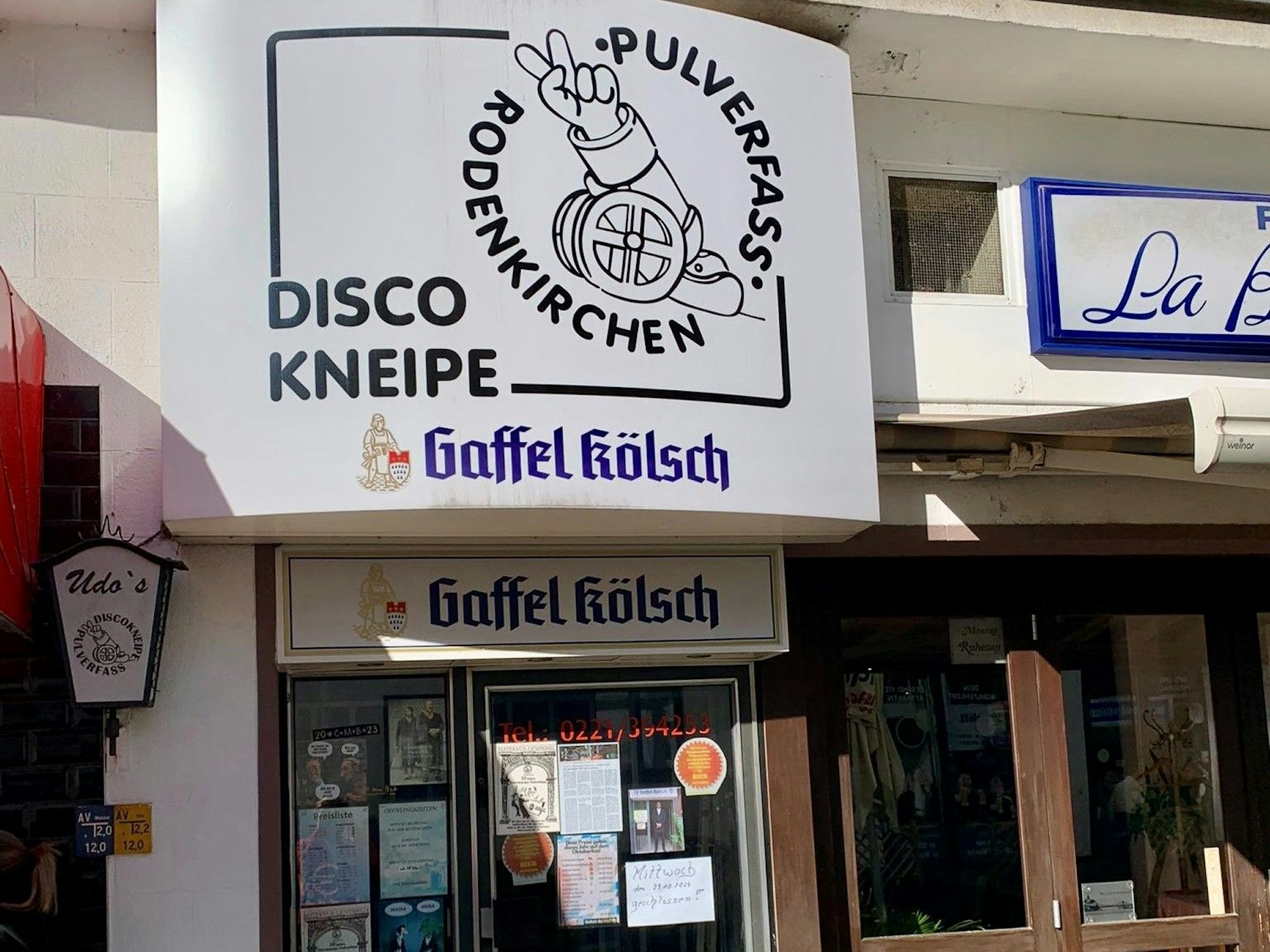 Über einem Hauseingang hängt ein Schild mit der Aufschrift „Discokneipe Pulverfass Rodenkirchen.“