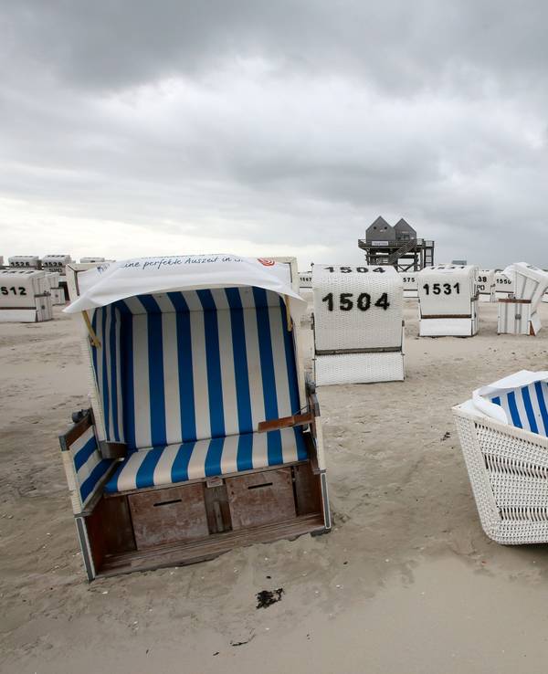 Umgekippte Strandkörbe liegen bei stürmischen Wetter am Strand von Sankt Peter Ording.
