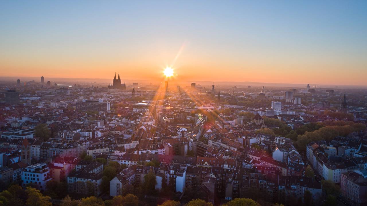 Blick über Köln bei Sonnenaufgang. Im Zentrum ist der Kölner Dom zu sehen.