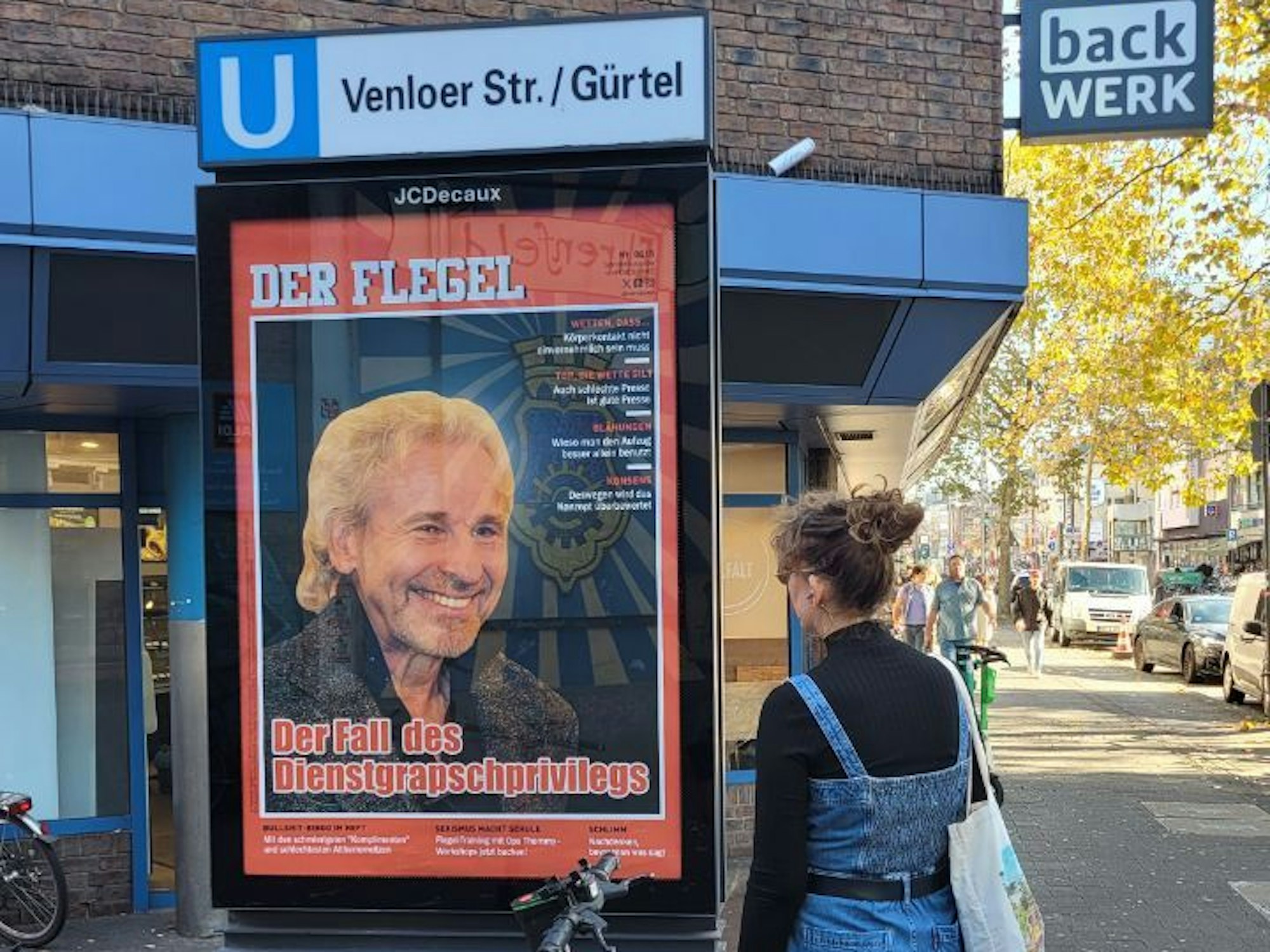 Frau steht vor Plakat von Thomas Gottschalk in Köln.