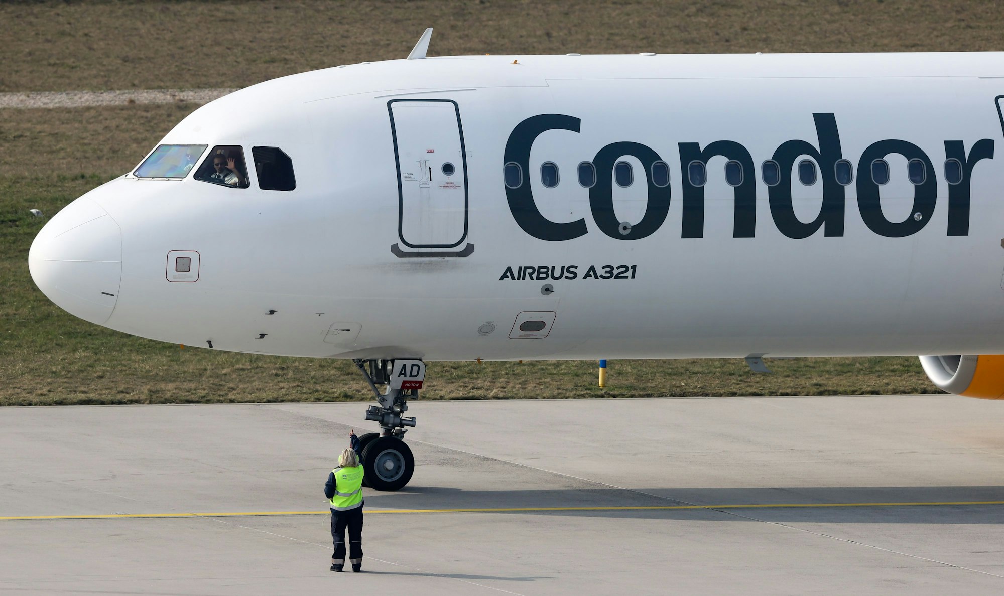Der Pilot einer Condor-Maschine mit Ziel Teneriffa winkt dem Bodenpersonal vor dem Start vom Flughafen Leipzig/Halle.