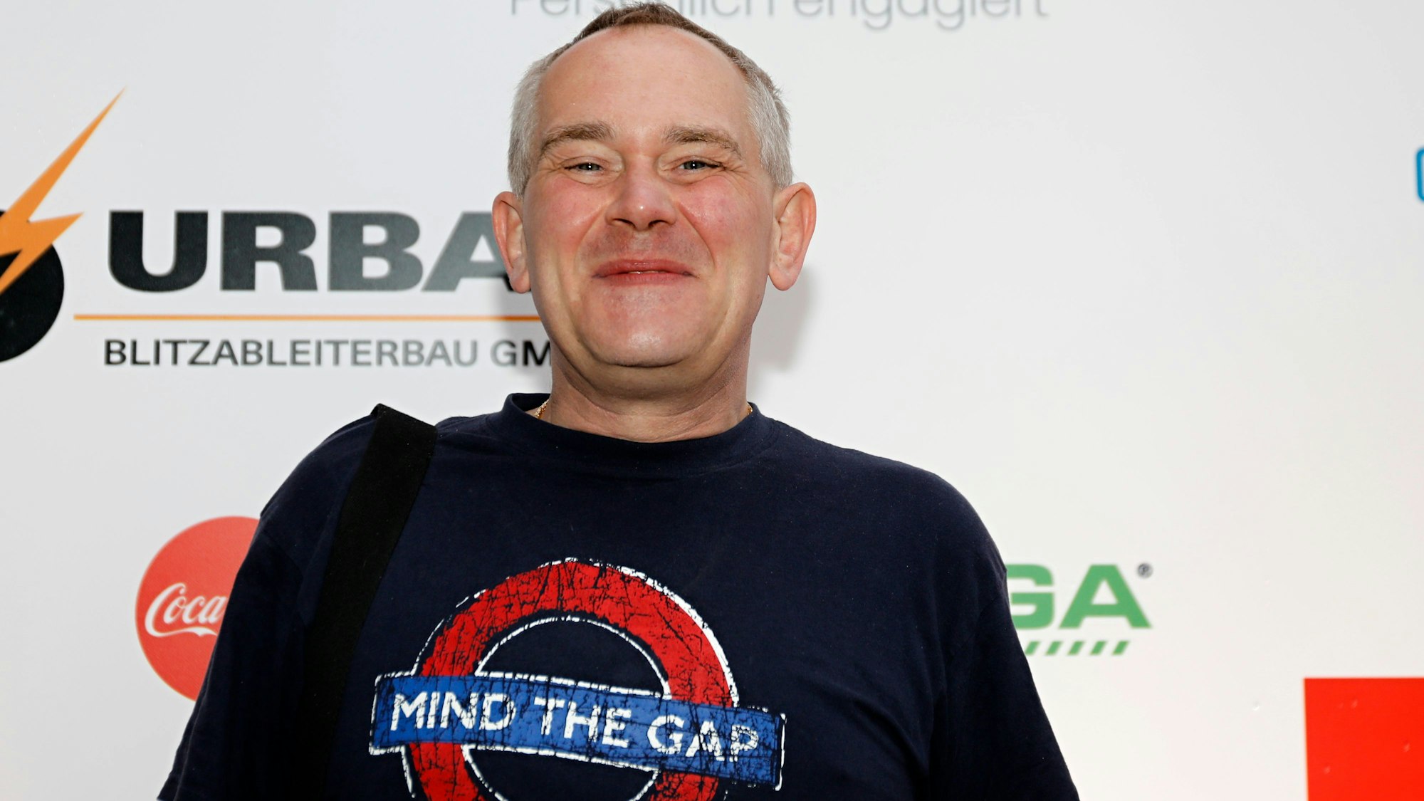 JP Weber steht vor einer Fotowand.