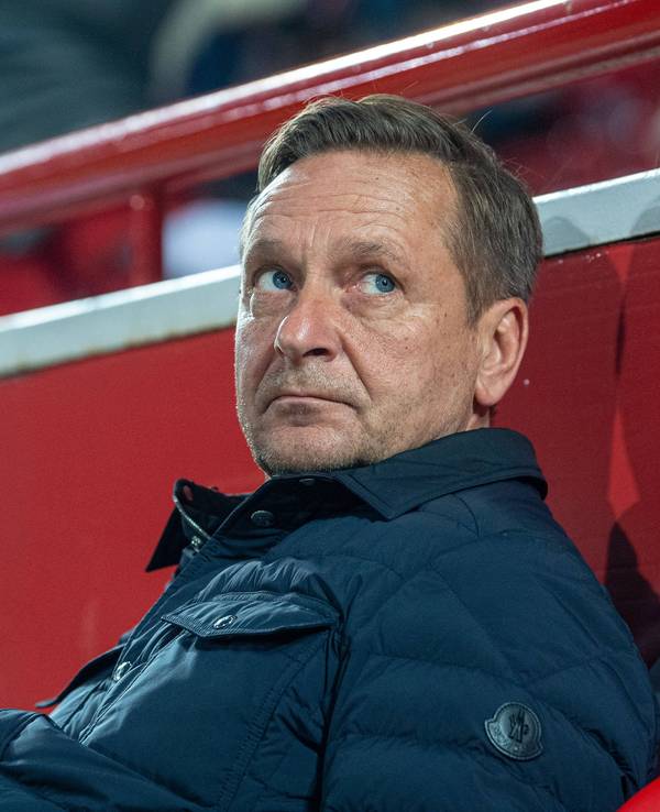 Horst Heldt sitzt auf der Trainerbank.