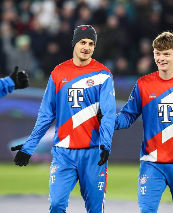 Josip Stanisic steht mit Mütze neben Paul Wanner auf dem Trainingsplatz des FC Bayern München.