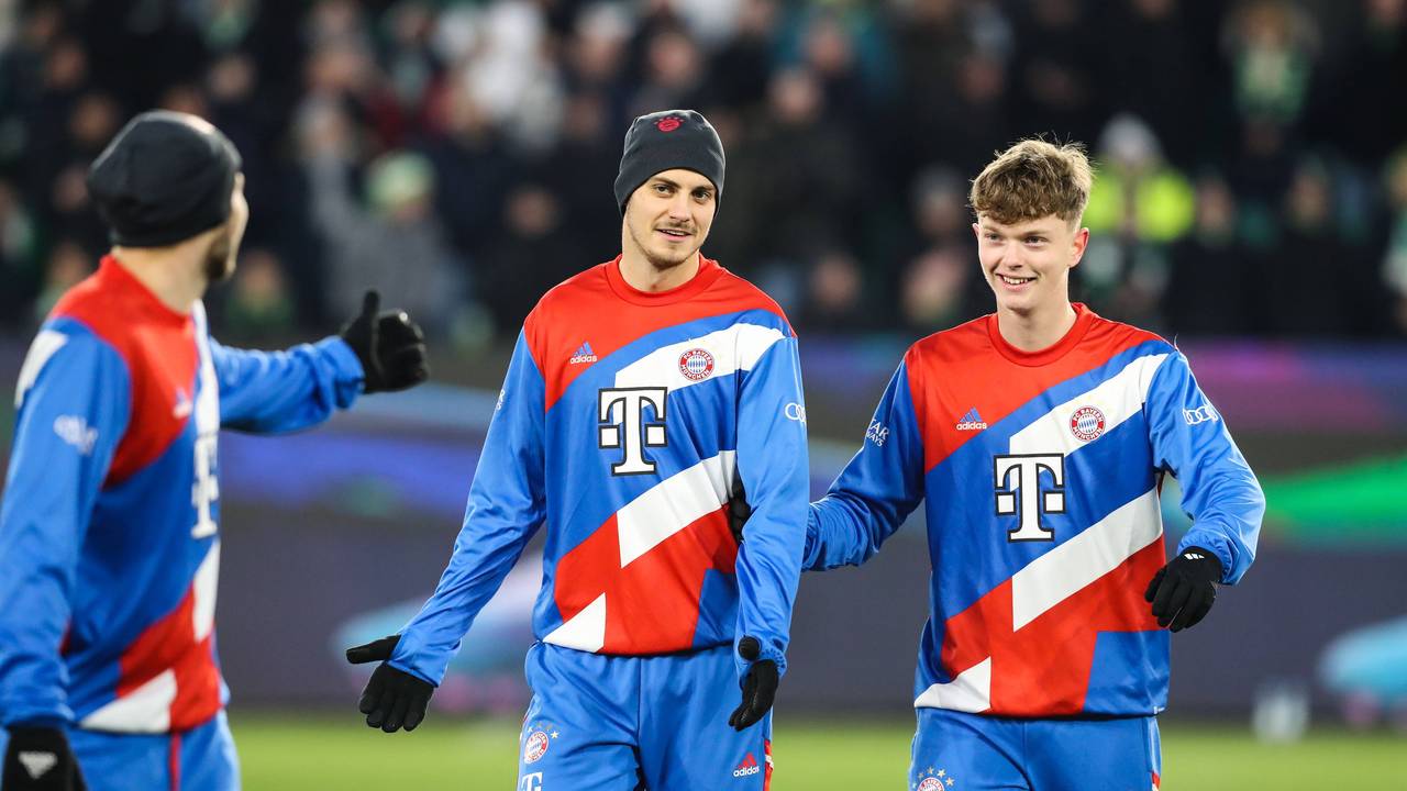 Josip Stanisic steht mit Mütze neben Paul Wanner auf dem Trainingsplatz des FC Bayern München.