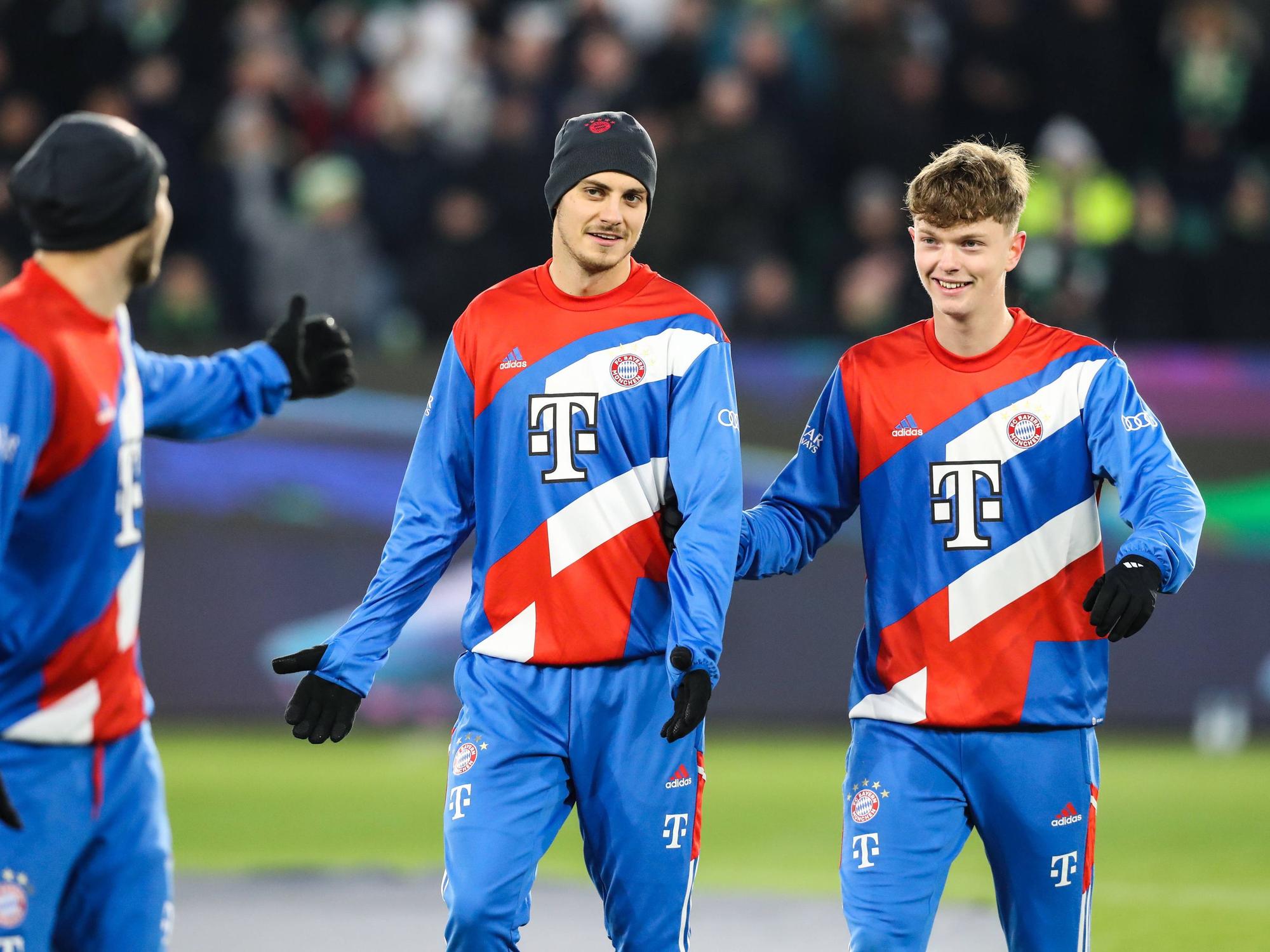 Josip Stanisic steht mit Mütze neben Paul Wanner auf dem Trainingsplatz des FC Bayern München.