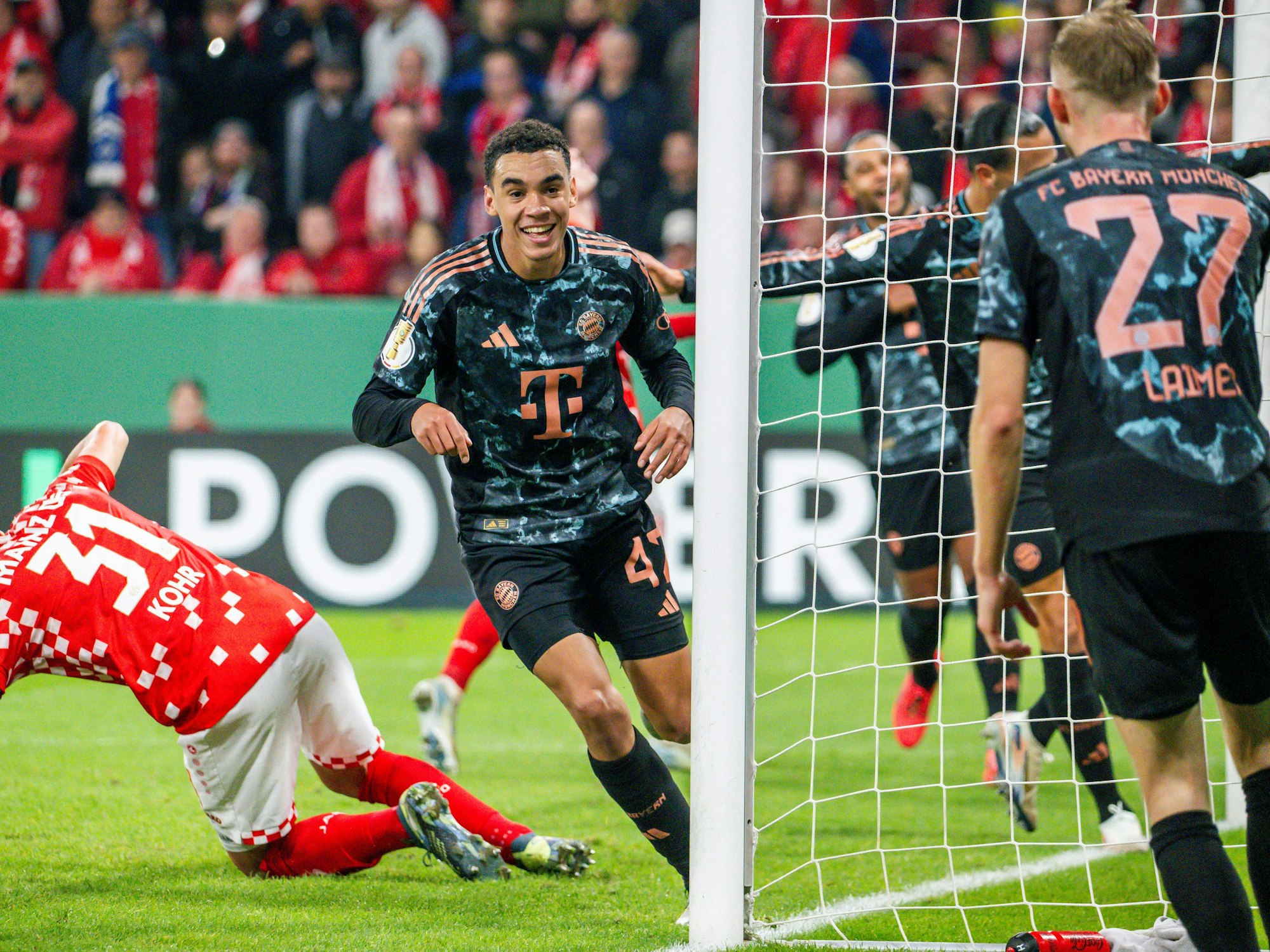 Bayerns Jamal Musiala (M) schiesst den Treffer zum 4:0 und jubelt mit seiner Mannschaft.