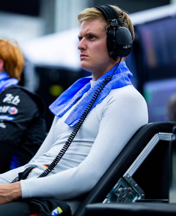 Mick Schumacher sitzt mit Kopfhörern im Fahrerbereich.
