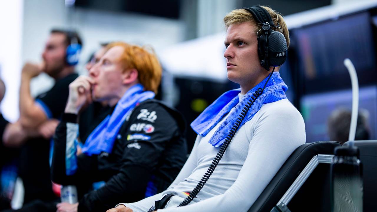 Mick Schumacher sitzt mit Kopfhörern im Fahrerbereich.