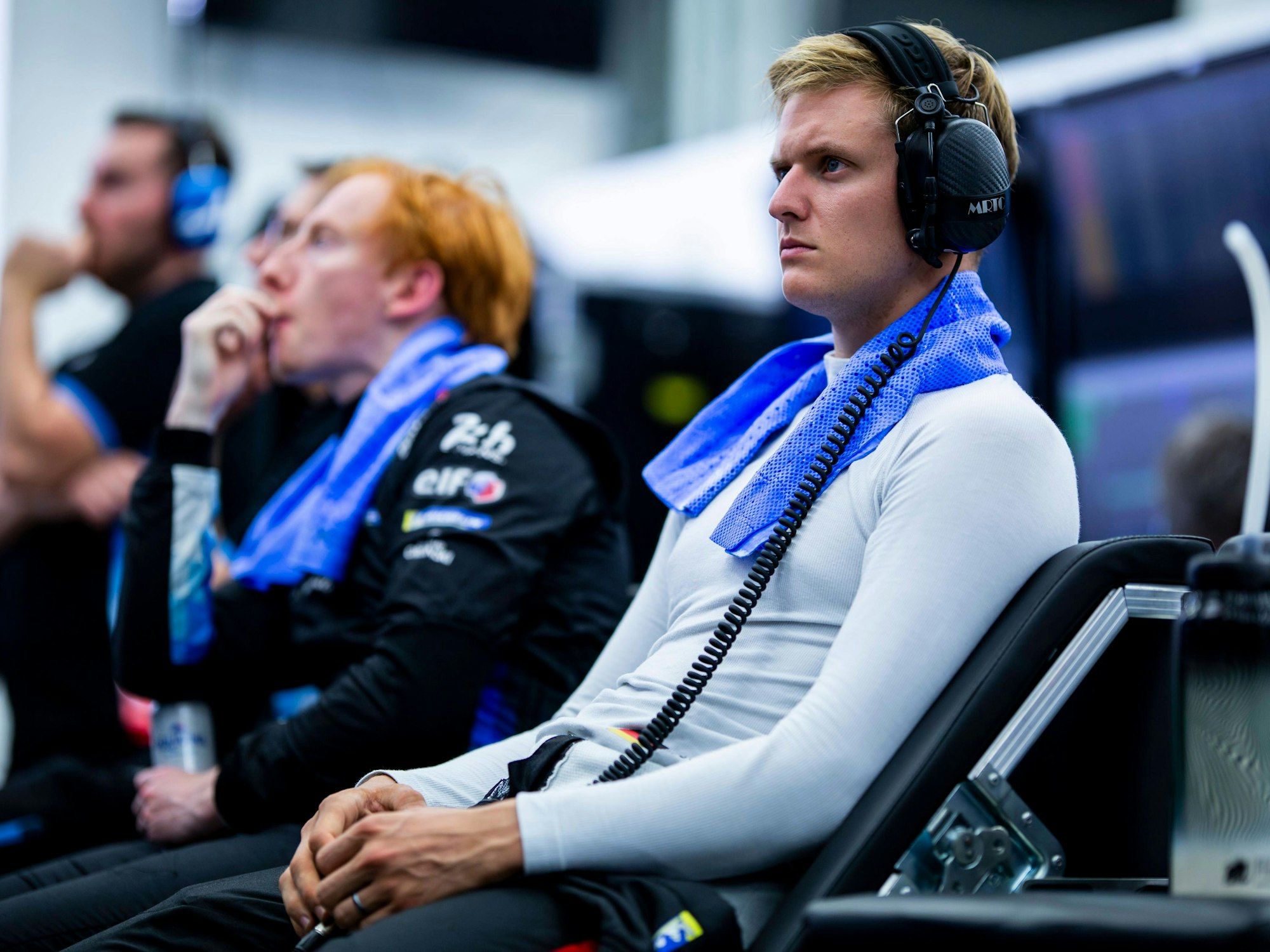 Mick Schumacher sitzt mit Kopfhörern im Fahrerbereich.