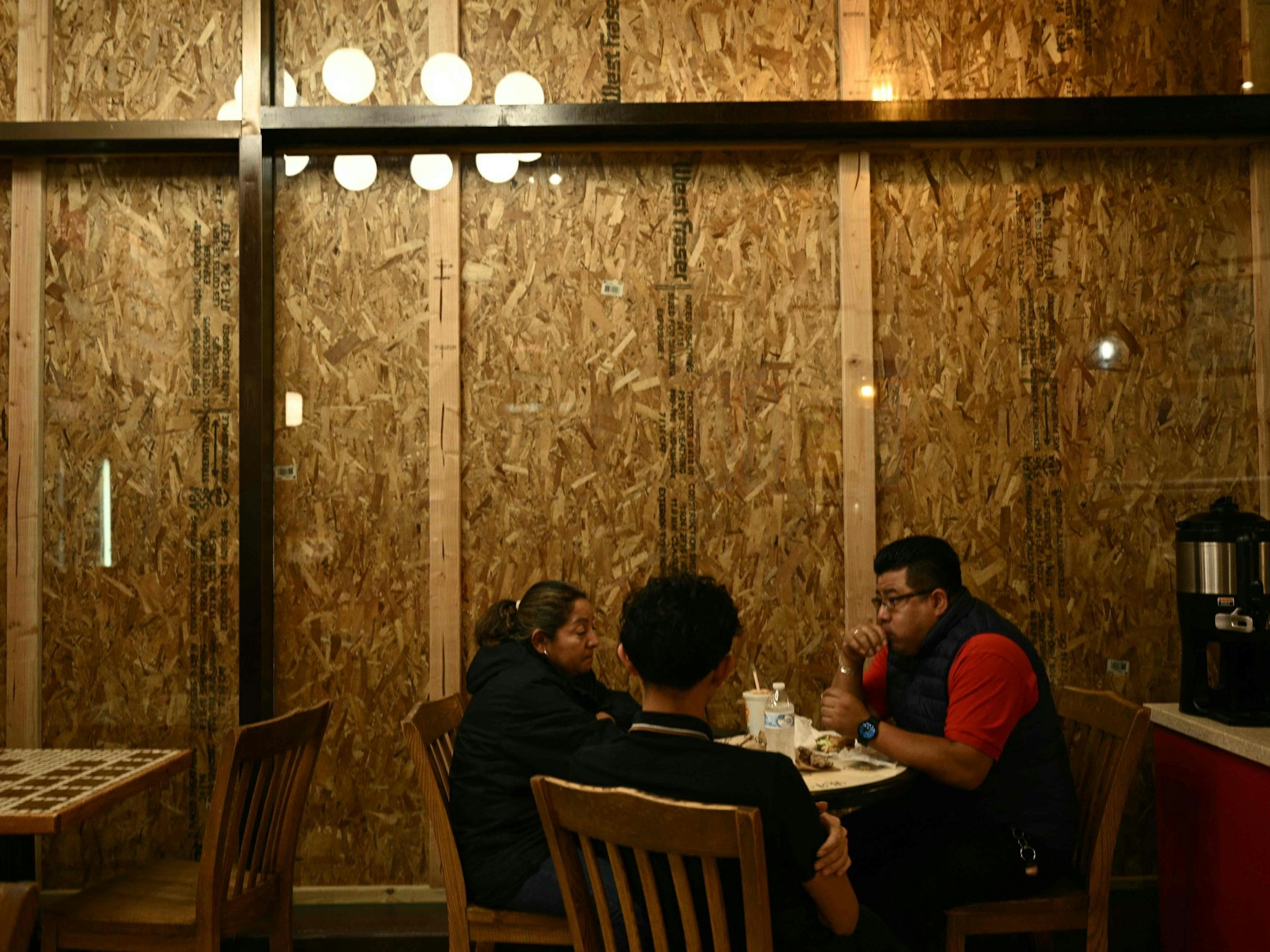 Besucher essen in einem mit Brettern vernagelten Restaurant in der Innenstadt von Washington ihr Sandwich.