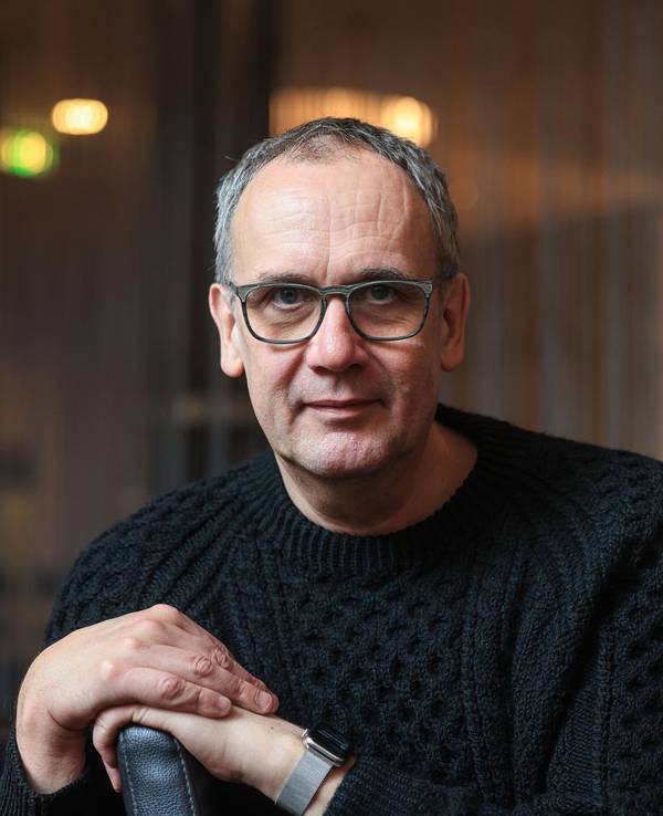 Volker Kutscher sitzt in einem Café in Köln und lächelt leicht in die Kamera.