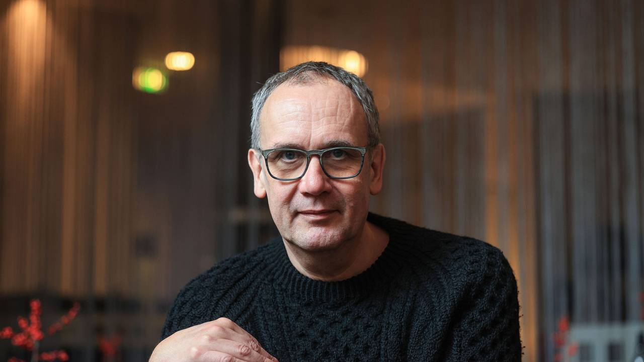 Volker Kutscher sitzt in einem Café in Köln und lächelt leicht in die Kamera.