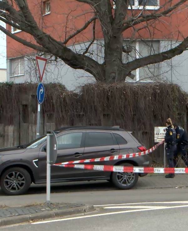Ein Auto steht auf einer Straße, im Hintergrund bringen Einsatzkräfte der Polizei Absperrband an.