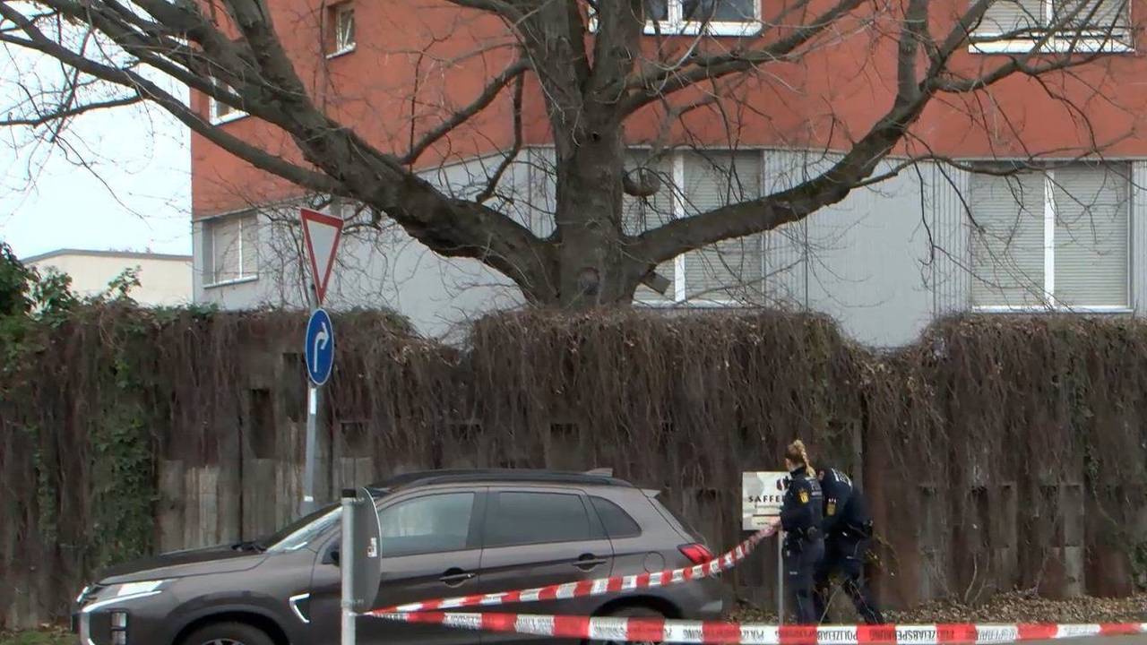 Ein Auto steht auf einer Straße, im Hintergrund bringen Einsatzkräfte der Polizei Absperrband an.