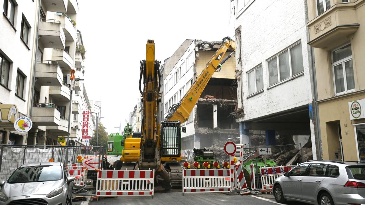 Eine gesperrte Straße mit einer großen Baustelle im Hintergrund. In der Antwerpener Straße in Köln wird die Grundschule abgerissen und neu aufgebaut.