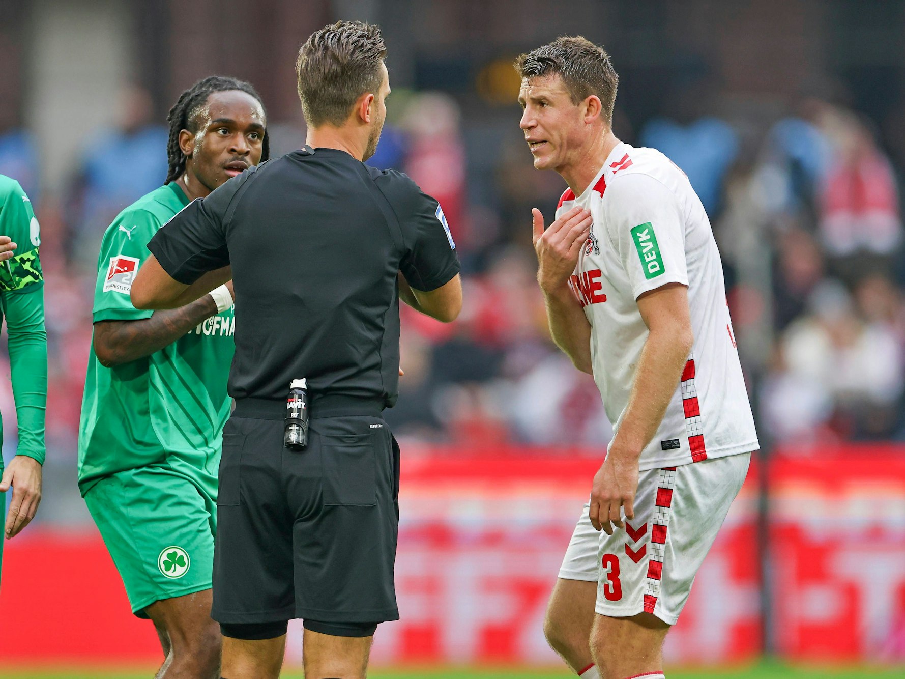 Dominique Heintz (1. FC Köln) diskutiert mit Noel Futkeu (Greuther Fürth) und Schiedsrichter Daniel Schlager.