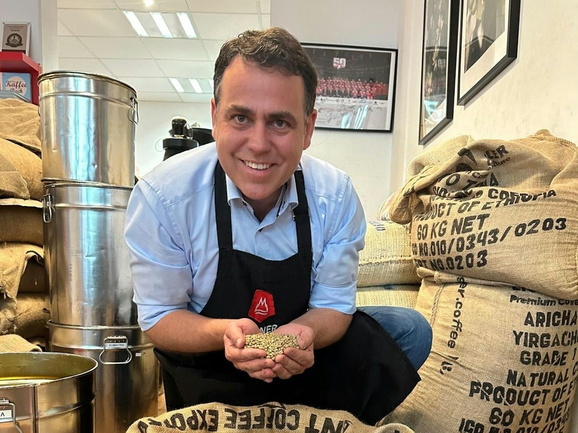 Georg Hembsch zeigt in seinem Laden einen großen Sack mit Rohkaffee.