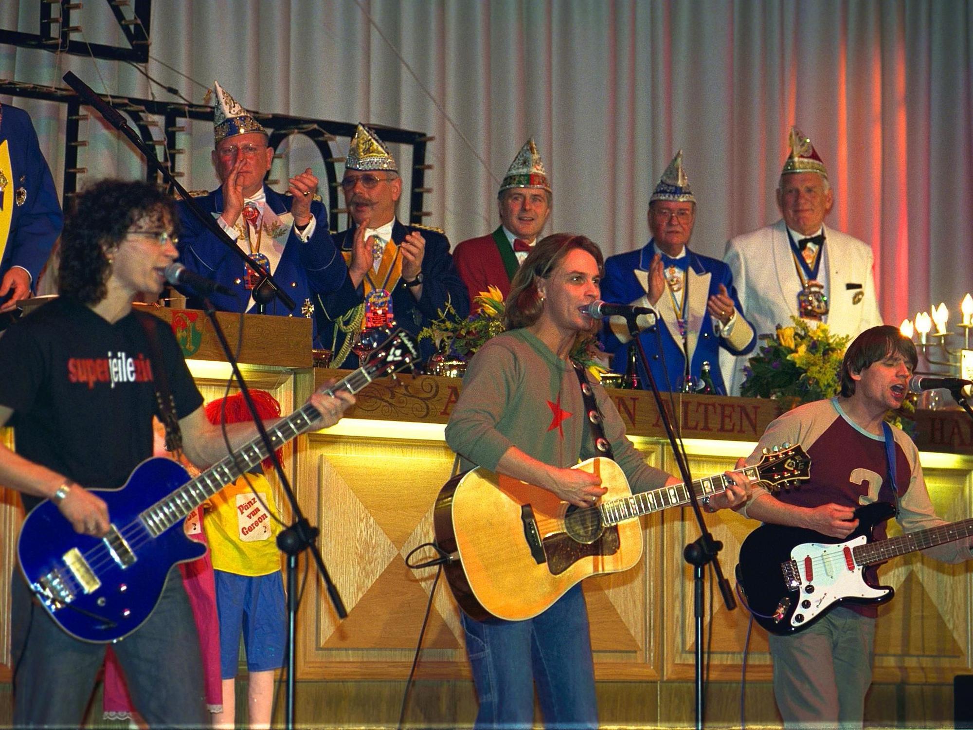 Die Band Brings spielt in einer Reihe auf der Bühne. Im Hintergrund der Elferrat.