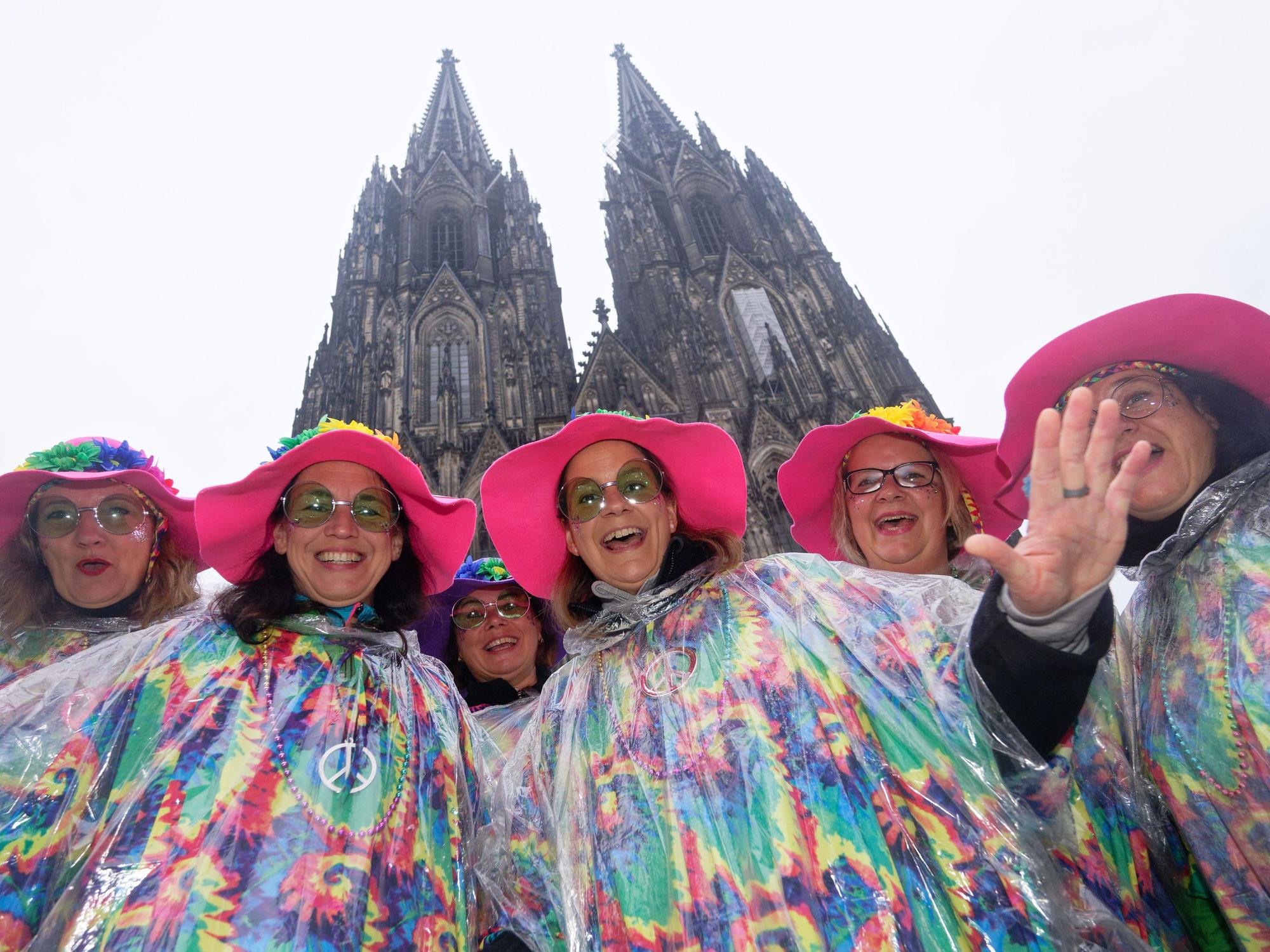 Karnevalistinnen aus dem Saarland aus posieren im Nieselregen vor dem Dom für ein Foto.