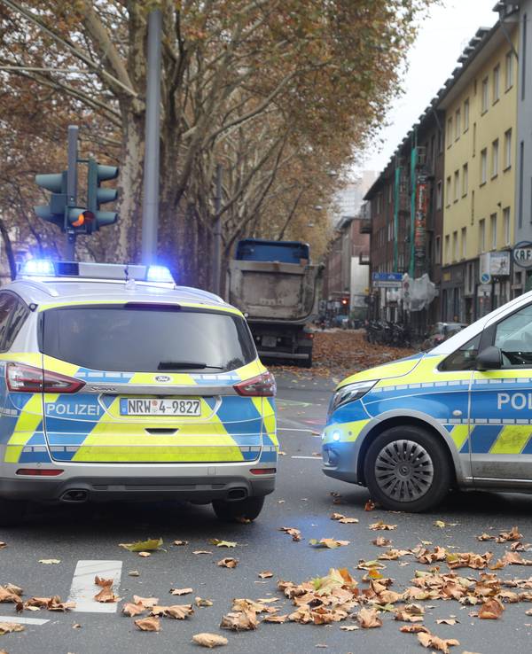 Zwei Polizeifahrzeuge stehen auf einer Straße.