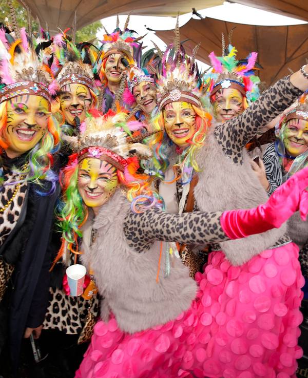 Mehrere junge Frauen tragen Oberteile im Leoparden-Muster und Federschmuck auf dem Kopf.