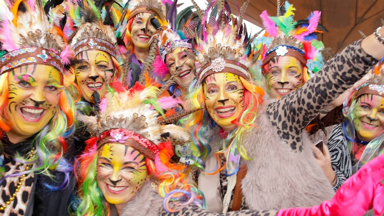 Mehrere junge Frauen tragen Oberteile im Leoparden-Muster und Federschmuck auf dem Kopf.