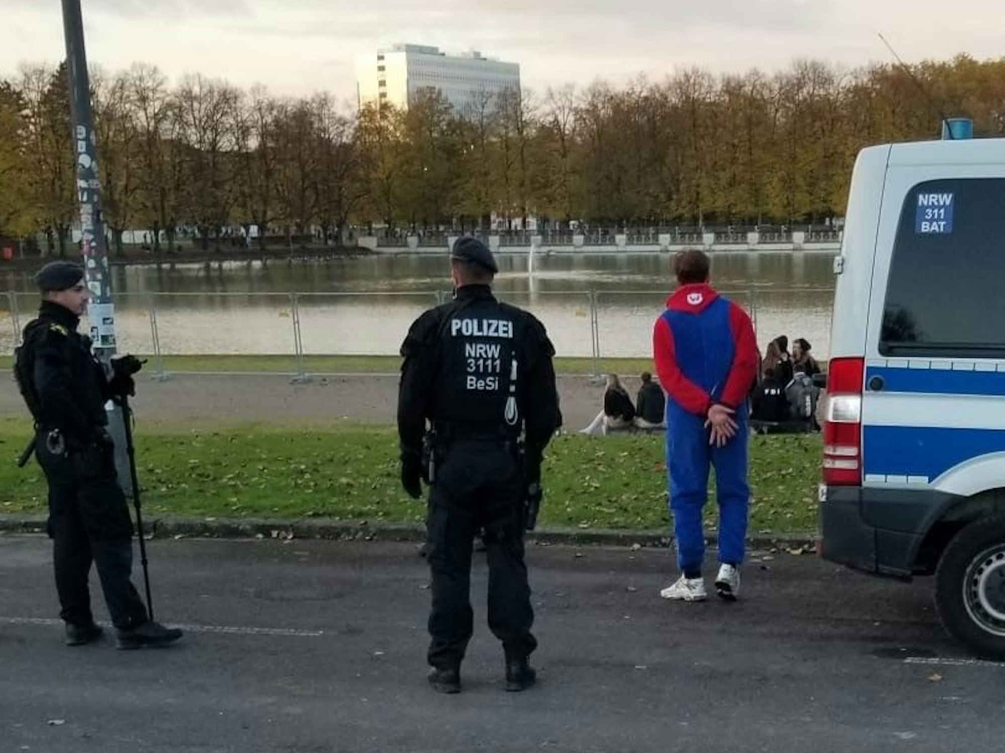 Einsatzkräfte der Polizei haben einem verkleideten Mann die Hände auf dem Rücken gefesselt.
