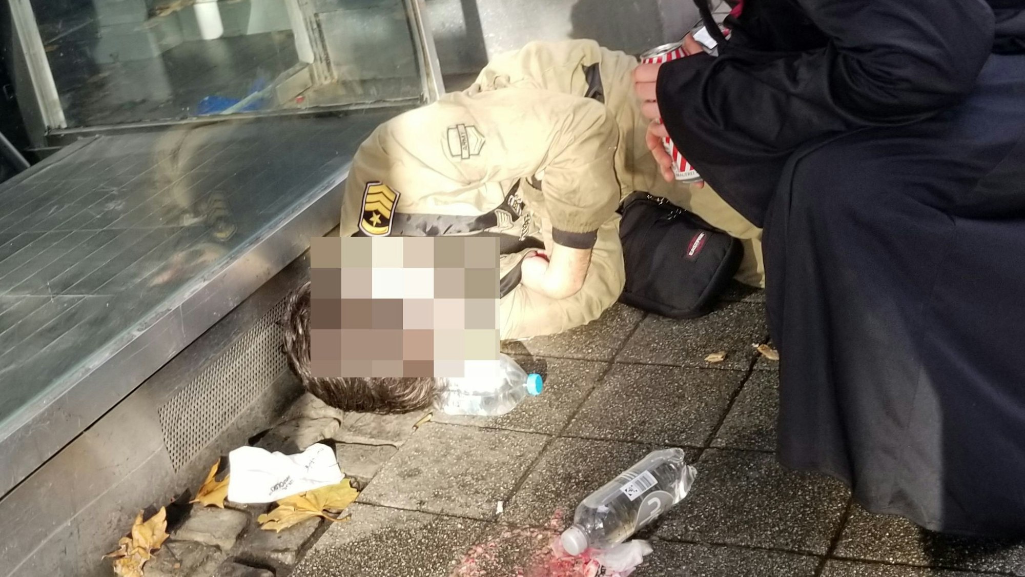 Ein junger Mann liegt auf dem Bürgersteig.