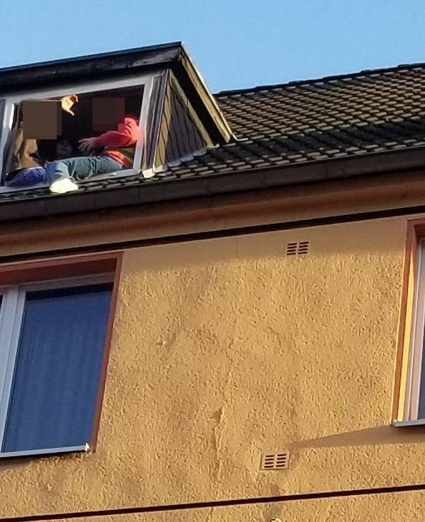 Zwei Personen sitzen gefährlich am Fenster in einer Dachgeschoss-Wohnung