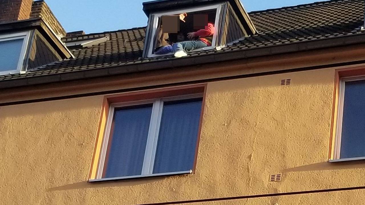 Zwei Personen sitzen gefährlich am Fenster in einer Dachgeschoss-Wohnung