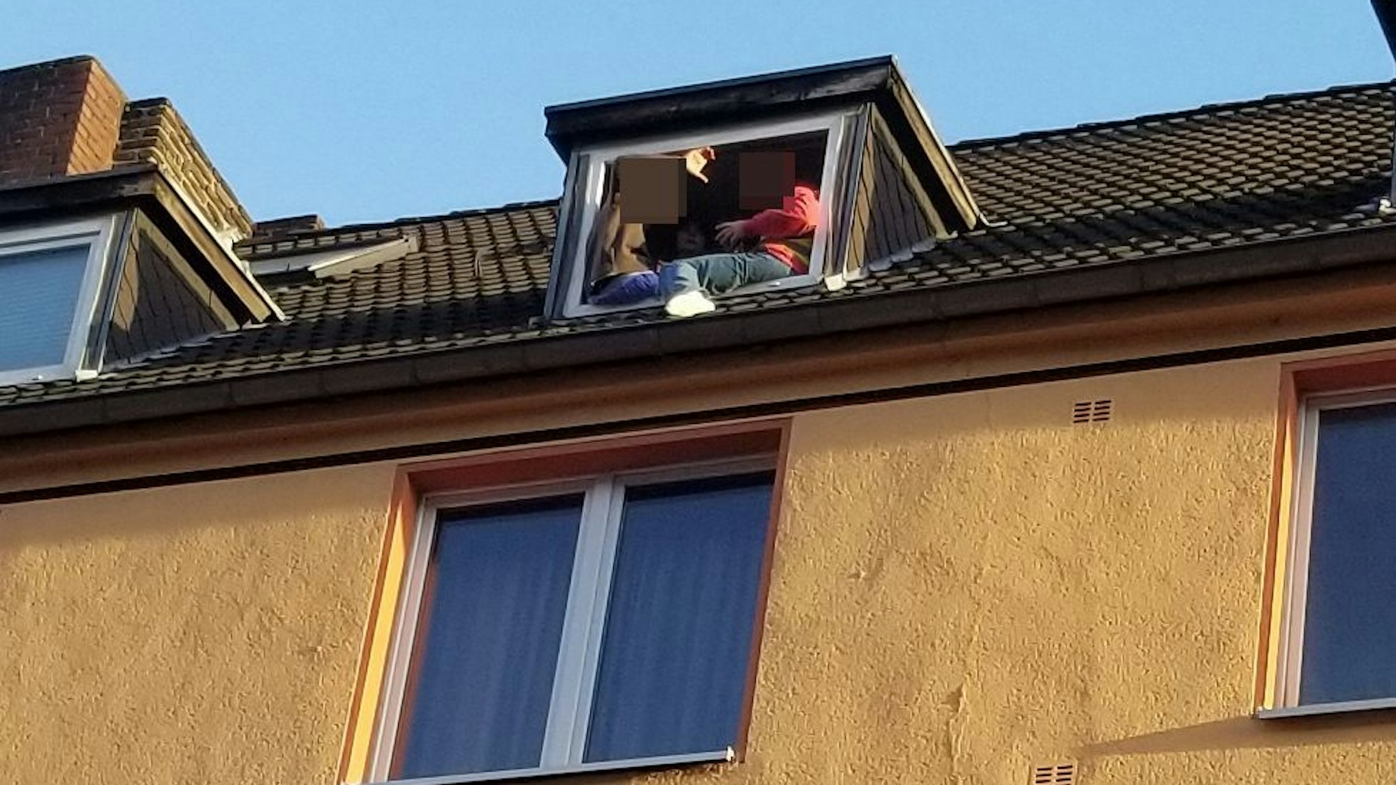 Zwei Personen sitzen gefährlich am Fenster in einer Dachgeschoss-Wohnung