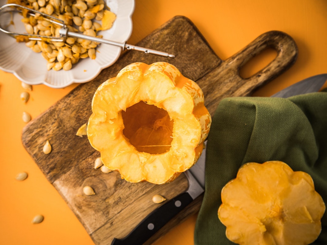 Ein ausgehöhlter Kürbis liegt auf einem Schneidebrett aus Holz.