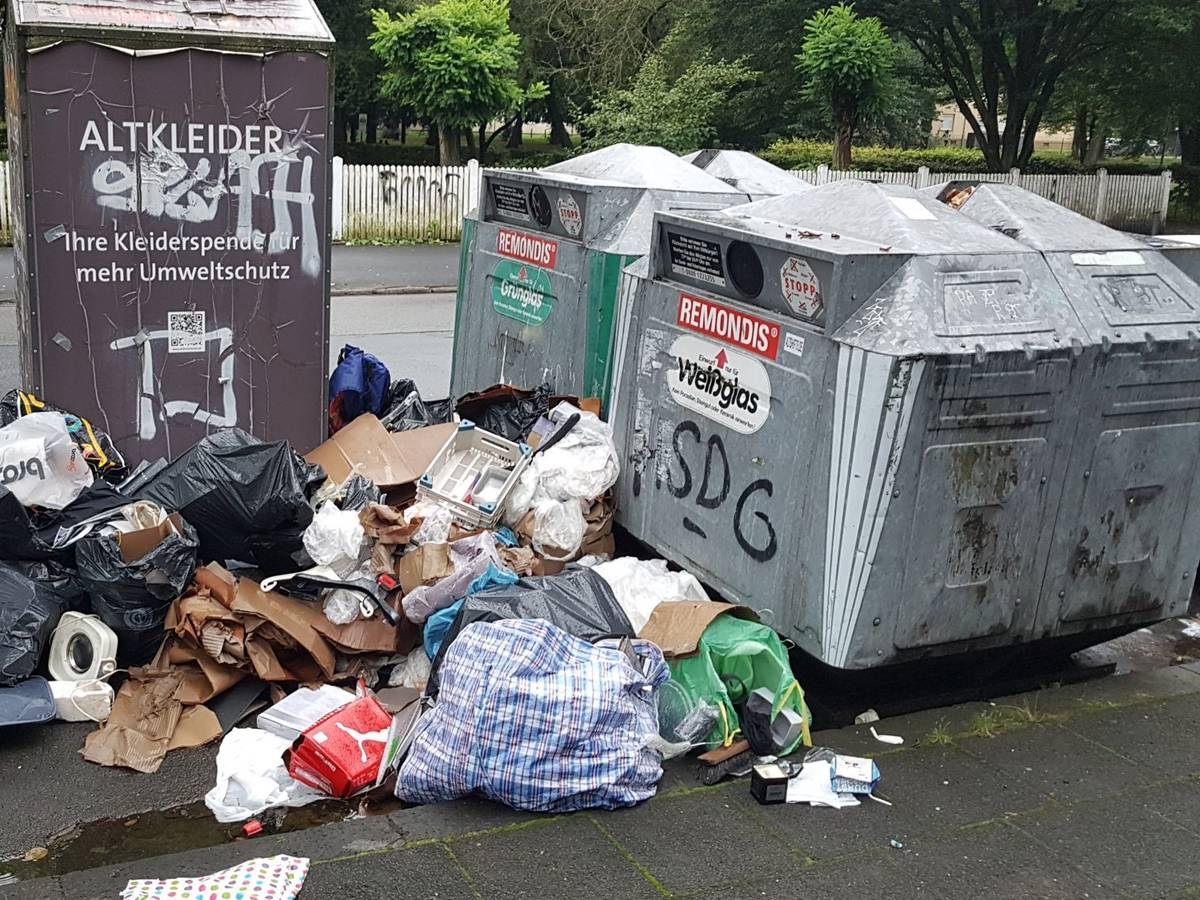 Müll steht neben einem Altkleidercontainer und zwei Glascontainern.
