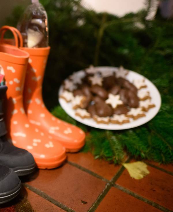Kinderstiefel, gefüllt mit Schoko-Nikoläusen, Mandarinen und weiteren Sachen, stehen vor einer Haustür eines Einfamilienhauses in der Region Hannover.