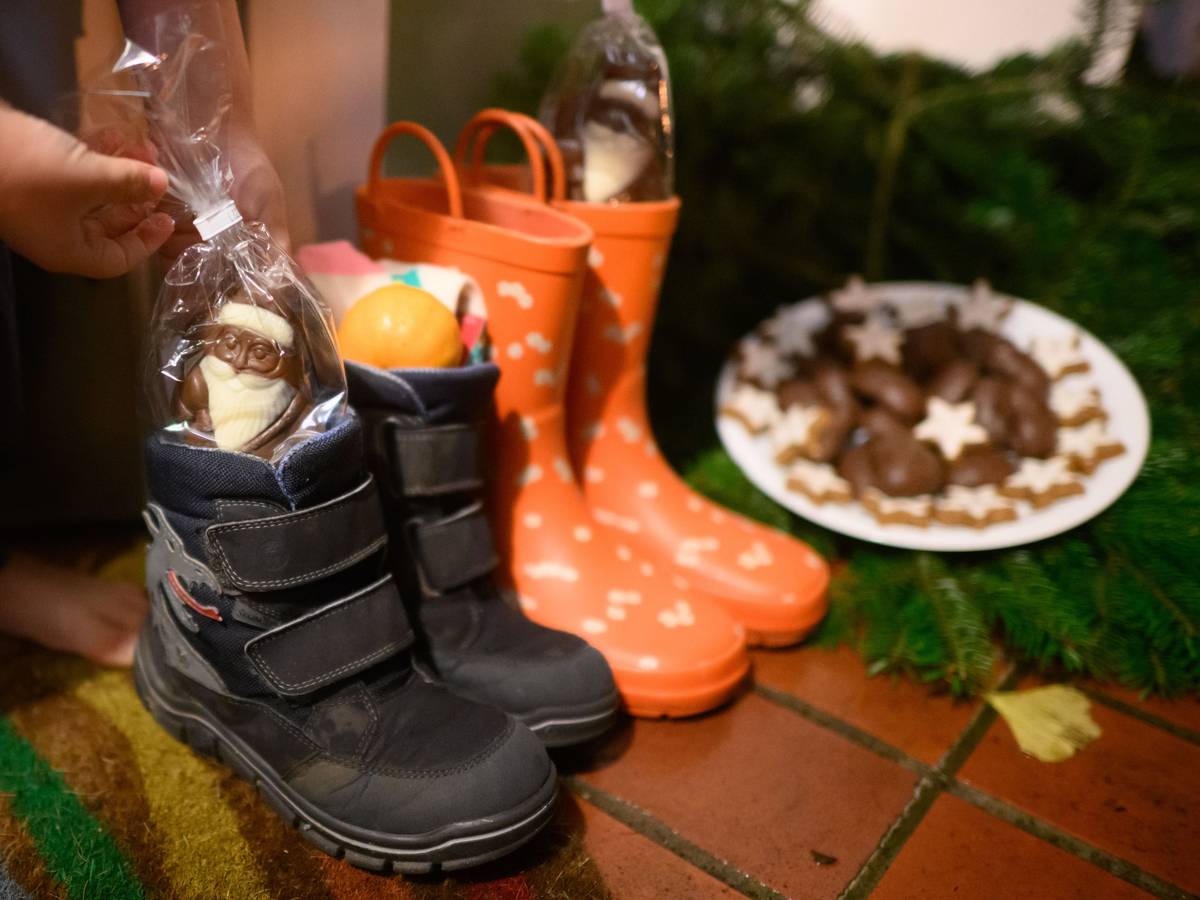 Kinderstiefel, gefüllt mit Schoko-Nikoläusen, Mandarinen und weiteren Sachen, stehen vor einer Haustür eines Einfamilienhauses in der Region Hannover.