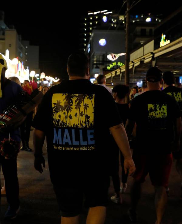 Männer, die ein T-Shirt mit der Aufschrift „Malle“ tragen, gehen durch die Schinkenstraße im sogenannten Ballermann-Viertel auf Mallorca.