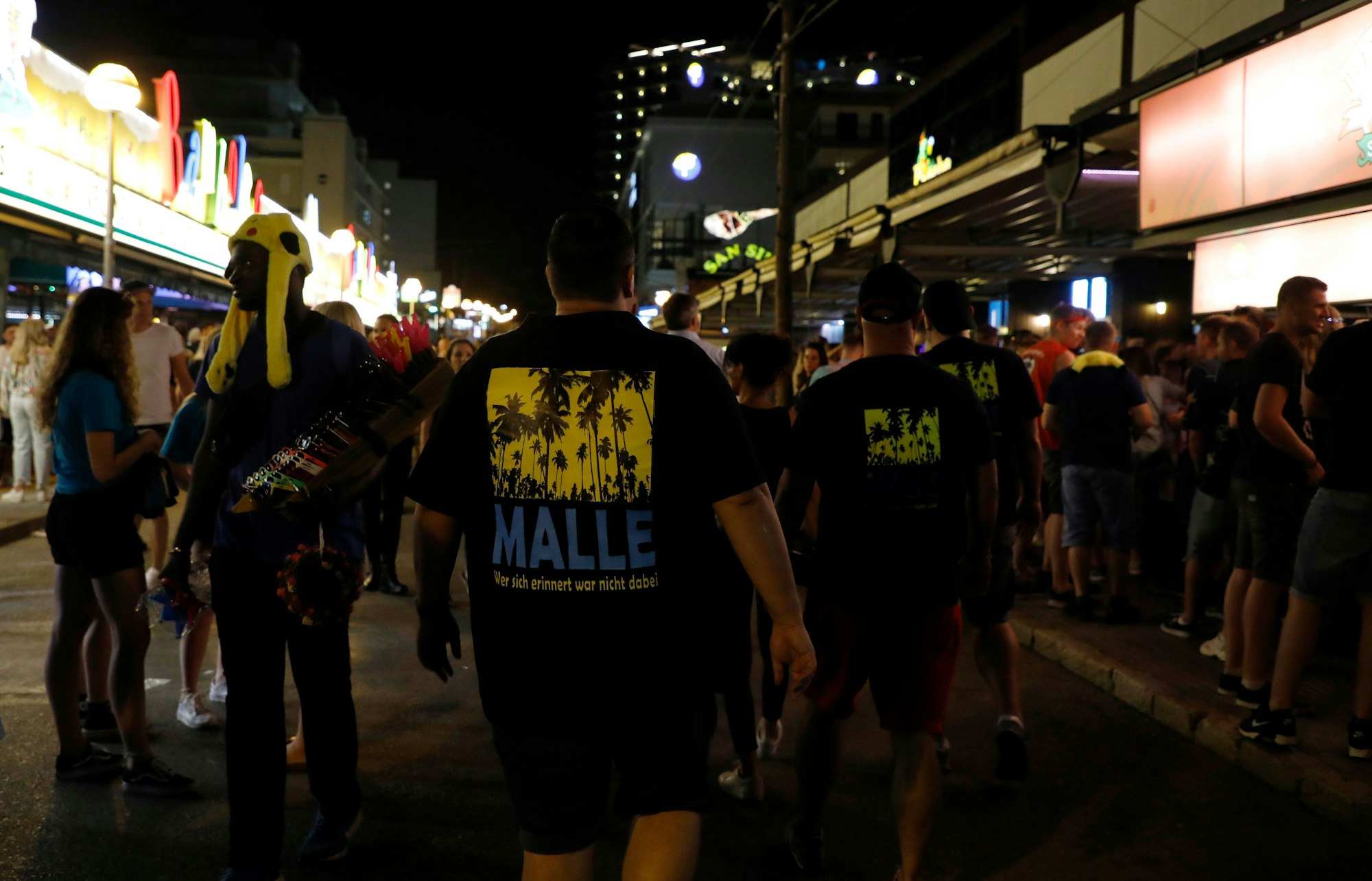 Männer, die ein T-Shirt mit der Aufschrift „Malle“ tragen, gehen durch die Schinkenstraße im sogenannten Ballermann-Viertel auf Mallorca.