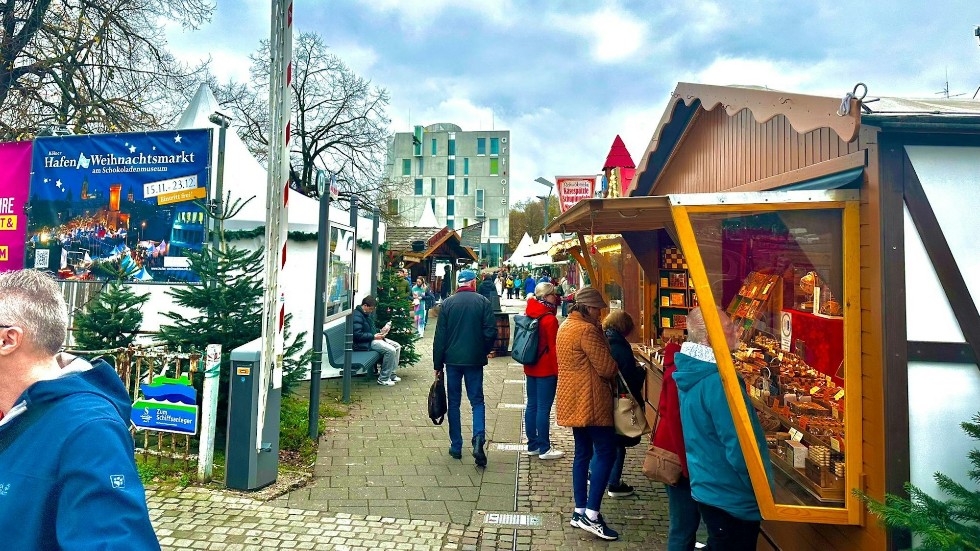 Menschen laufen über Kölner Hafenweihnachtsmarkt.