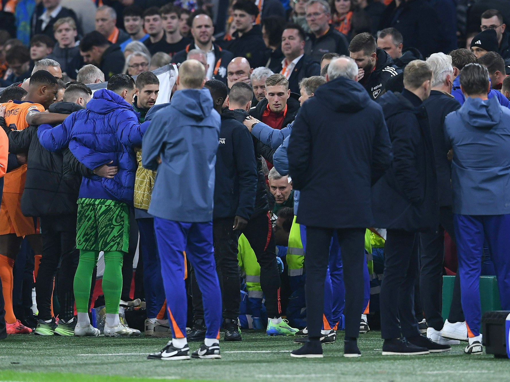 Spieler und Betreuer der Nationalmannschaften der Niederlande und Ungarn bilden einen menschlichen Sichtschutz.