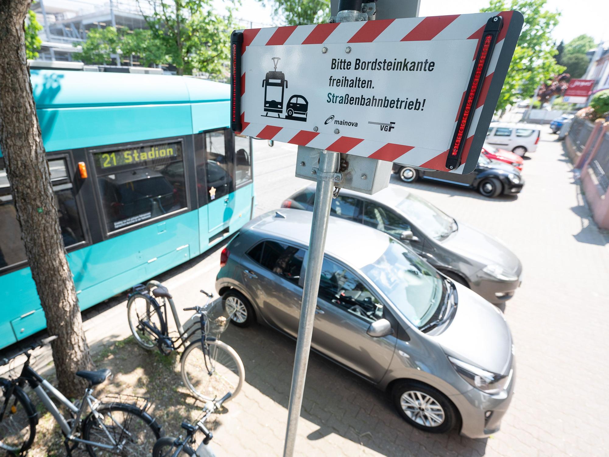 Eine Straßenbahn fährt auf der Schwarzwaldstraße an einem Auto vorbei, das knapp an den Schienen geparkt ist.