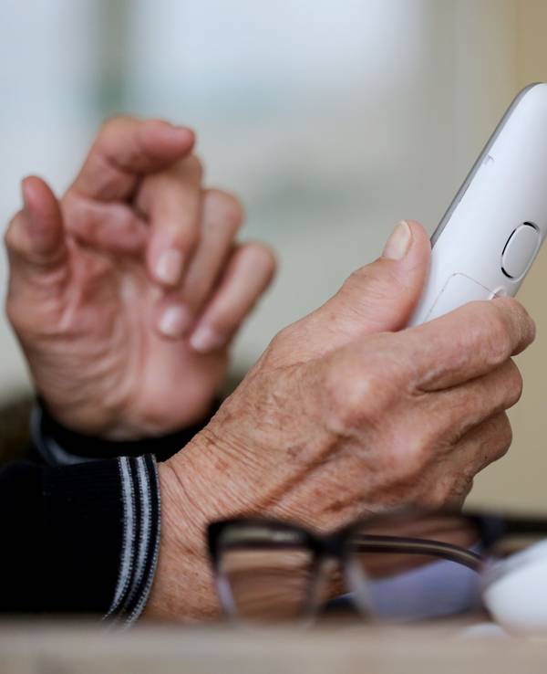 Eine ältere Dame nimmt in ihrer Wohnung ein Telefongespräch an.