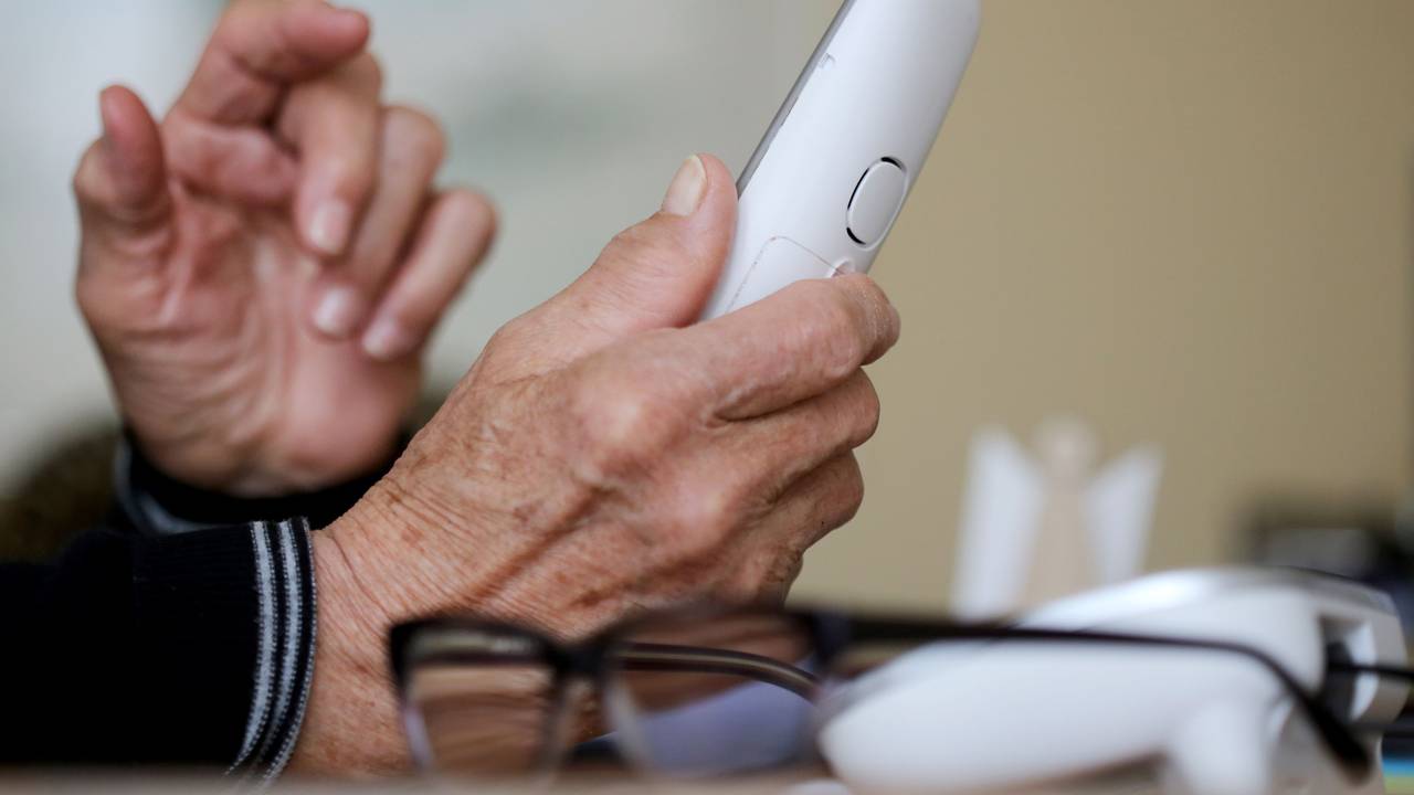 Eine ältere Dame nimmt in ihrer Wohnung ein Telefongespräch an.