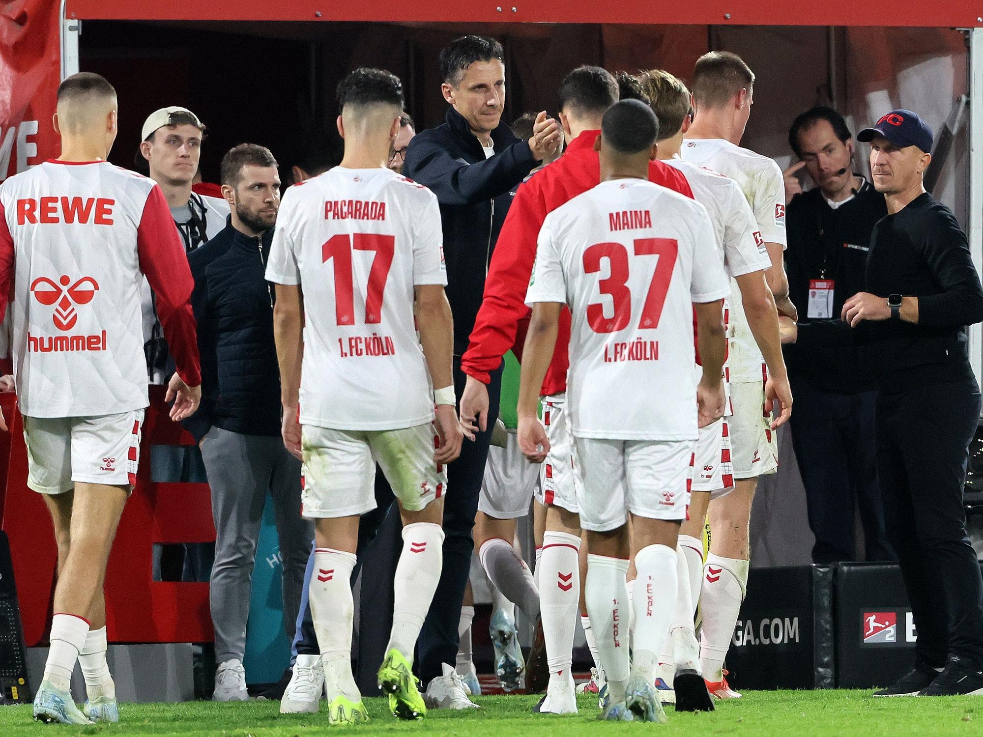 Christian Keller und Gerhard Struber klatschen mit den Spielern des 1. FC Köln ab.