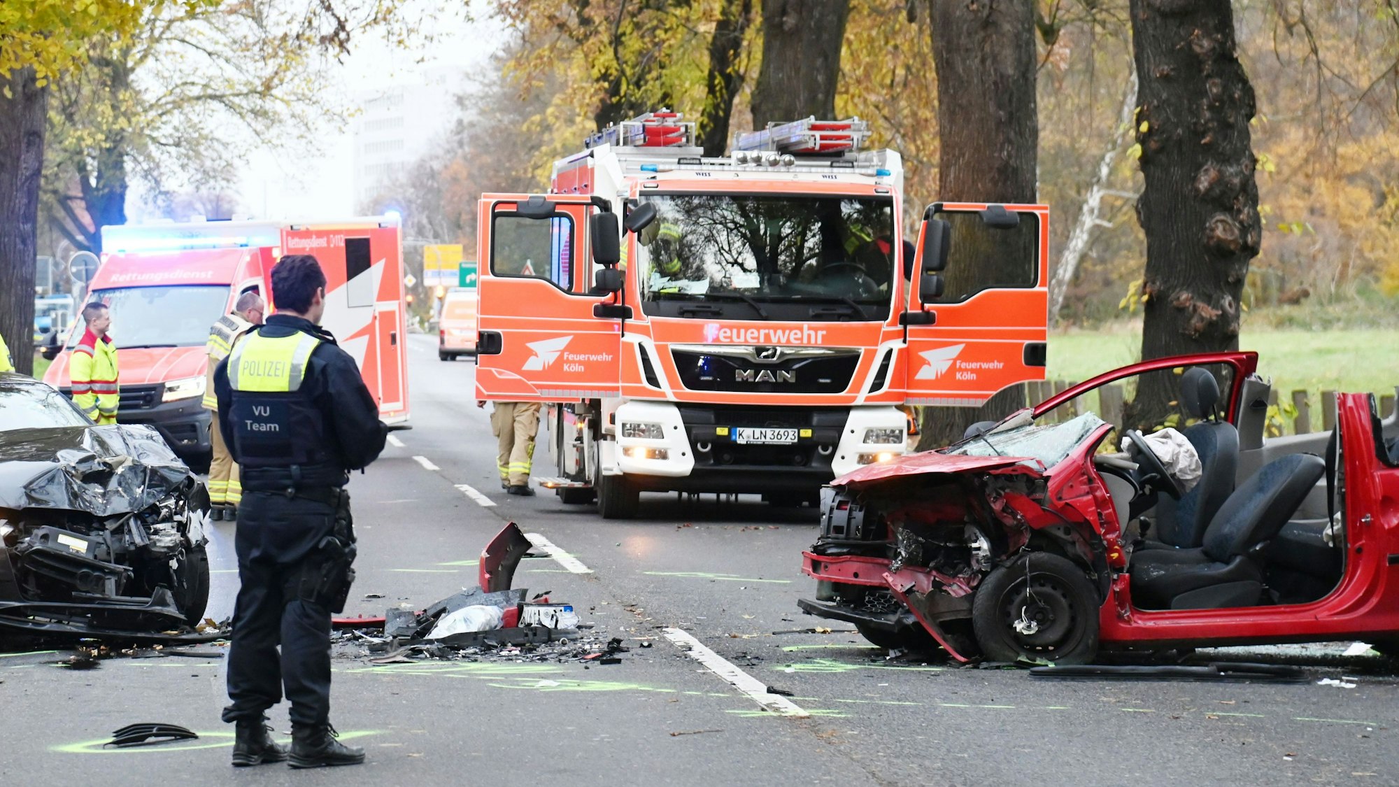 Zwei völlig zerstörte Autos stehen auf einer Straße, Trümmerteile liege auf der Fahrbahn.