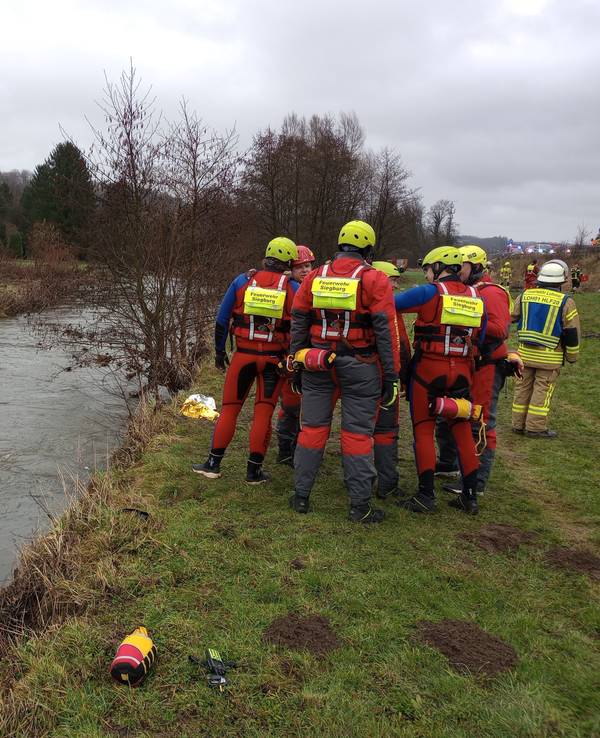 Feuerwehrleute stehen neben einem Auto im Fluss Sülz.
