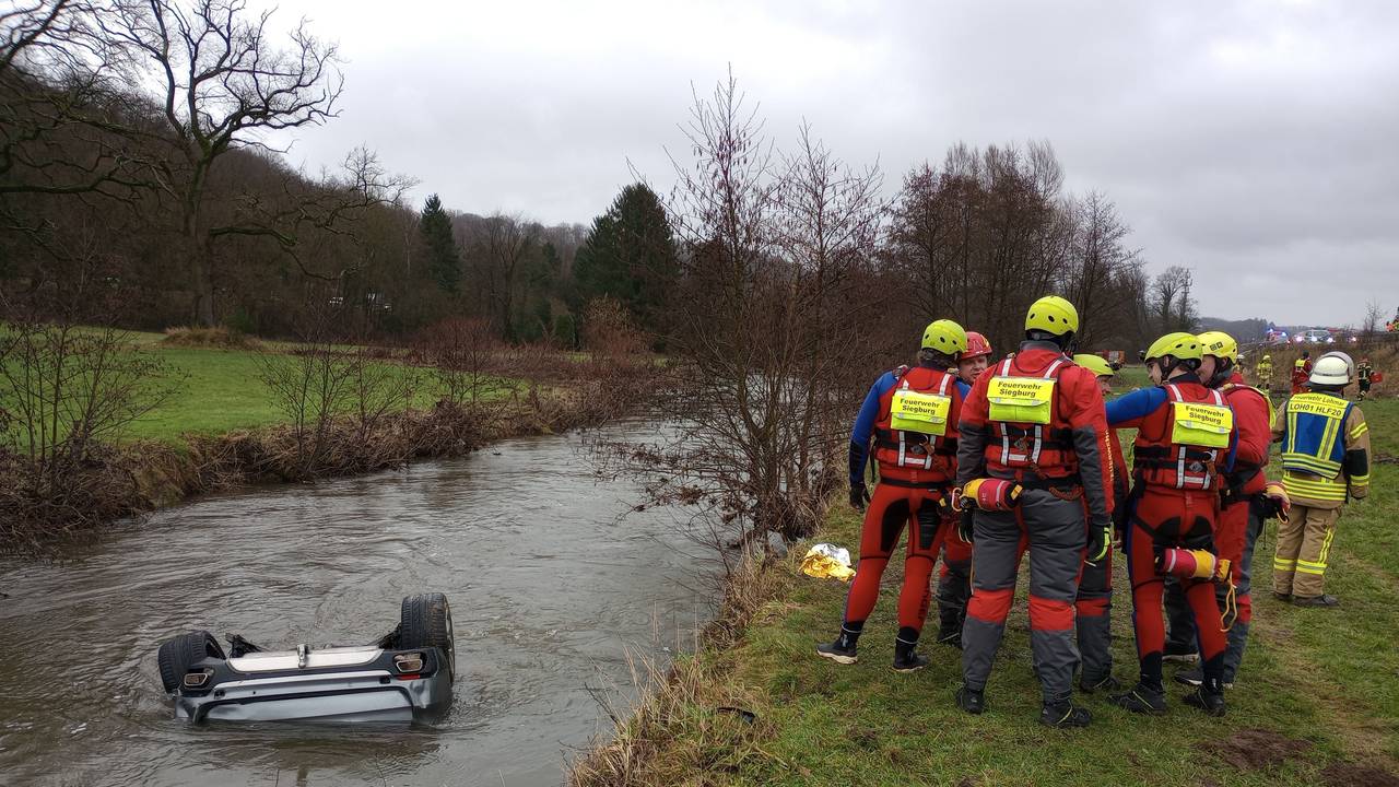 Feuerwehrleute stehen neben einem Auto im Fluss Sülz.