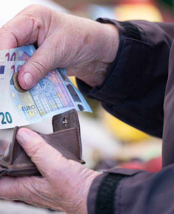 Eine Frau sortiert auf einem Wochenmarkt das Wechselgeld für ihre Einkäufe in ein Portemonnaie.